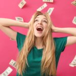 Mulher jovem feliz e notas de dólar caindo na cor de fundo - Fotos do Canva