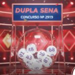 Ilustração 3D de um sorteio da Dupla Sena, concurso número 2919. O globo de cristal exibe bolas numeradas sob um letreiro vermelho. O ambiente é decorado com luzes vermelhas intensas e confetes caindo.