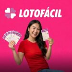 Mulher sorridente segurando vários volantes da Lotofácil contra um fundo rosa.