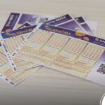 Bilhete de apostas da loteria +Milionária da Caixa sobre uma mesa.