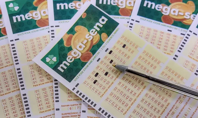Bilhetes da mega sena empilhados em mesa com o central sendo preenchido