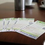 Bilhetes da loteria Super Sete alinhados em uma mesa de madeira.