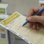 Pessoa marcando os números de um bilhete da Dia de Sorte em uma mesa de vidro