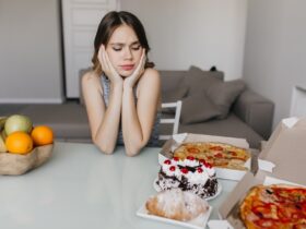 mulher encaracolada triste olhando para o bolo durante a dieta loira linda modelo feminino posando com frutas e pizza