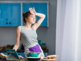 mulher limpando testa em cozinha