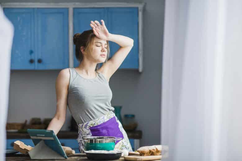 mulher limpando testa em cozinha