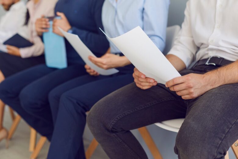 Candidatos a emprego nervosos esperando pela entrevista e lendo seus currículos repetidamente - Fotos do Canva