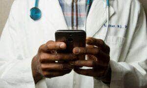 Médico com estetoscópio fala no celular. Foto: National Cancer Institute/Unsplash