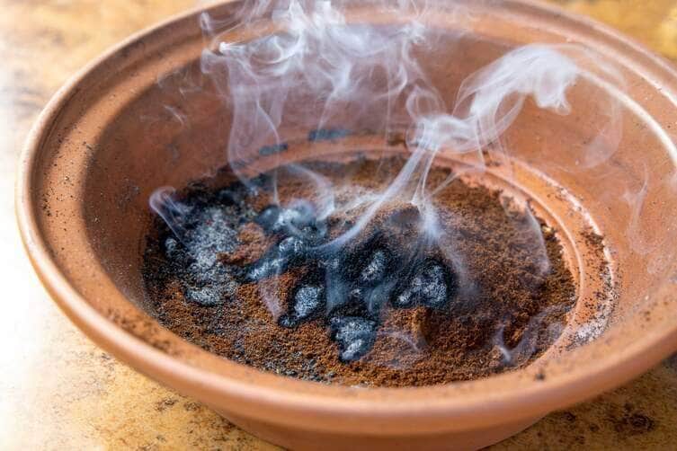 Burning coffee grounds for mosquito and wasp repellent in clay bowl producing burned coffee smoke for banishing insects. - Fotos do Canva
