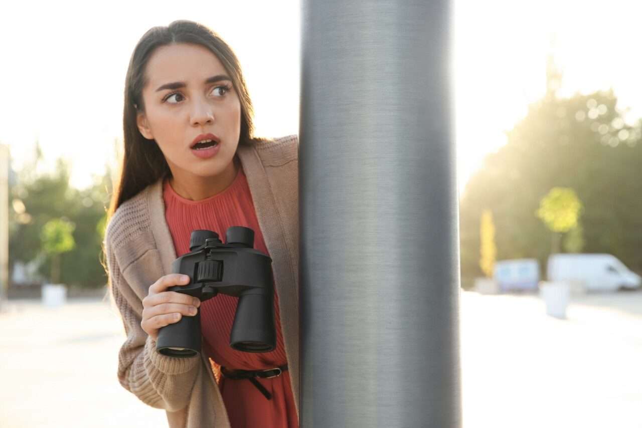 Mulher ciumenta com binóculos espionando ex-namorado ao ar livre - Fotos do Canva