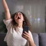 Animado mulher comemorando sucesso segurando o telefone móvel - Fotos do Canva