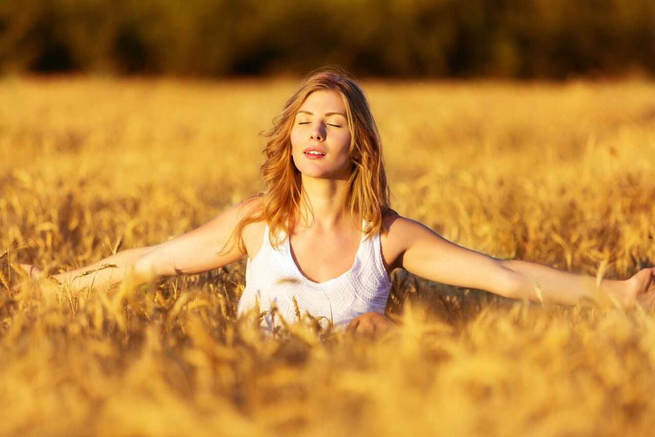 Mulher jovem e bonita entre o campo de trigo - Fotos do Canva