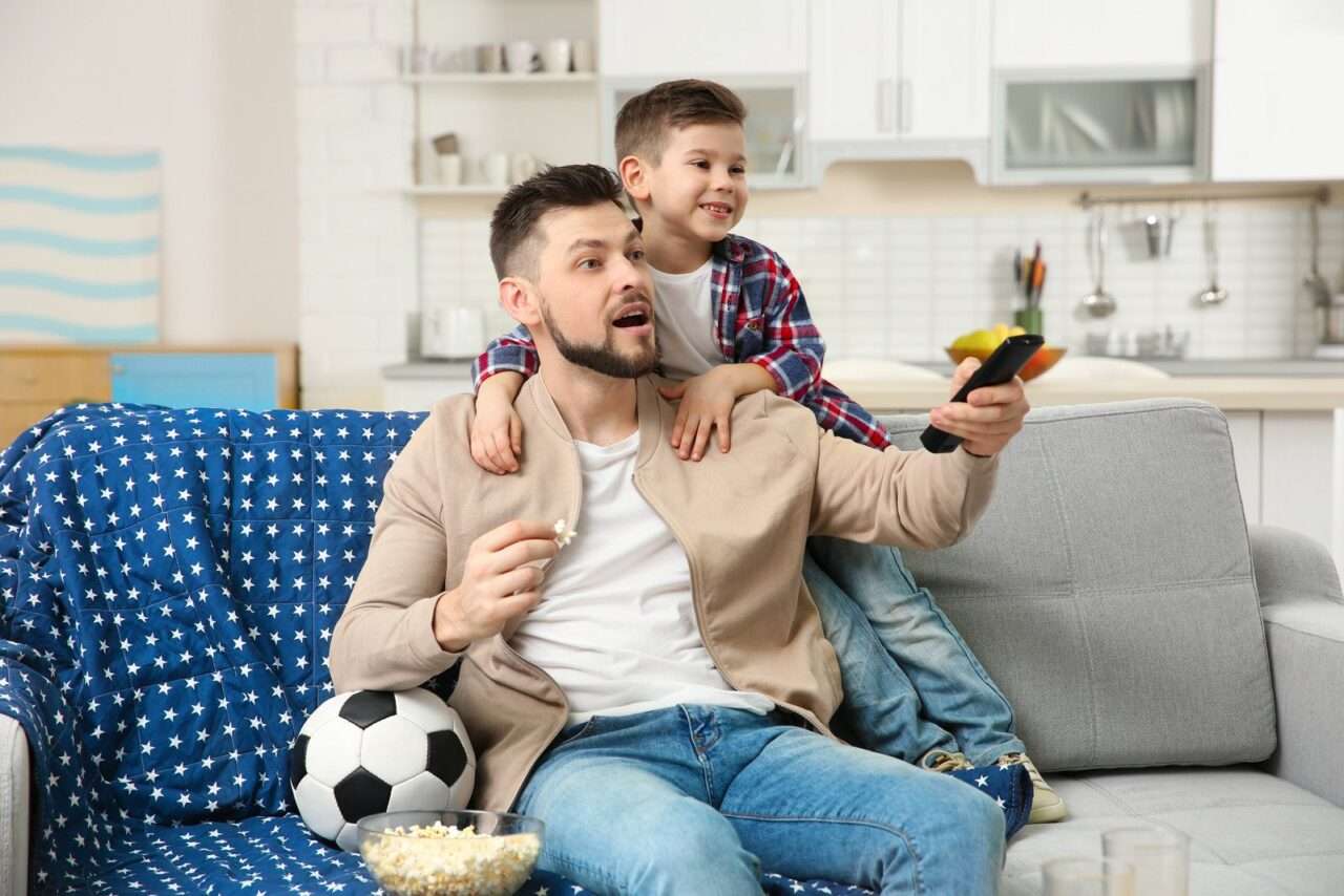 Pai e filho assistindo futebol na TV - Fotos do Canva