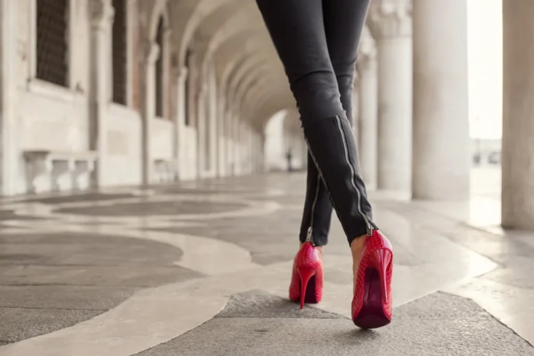 Mulher caminhando com calças pretas e salto alto vermelho - Fotos do Canva1