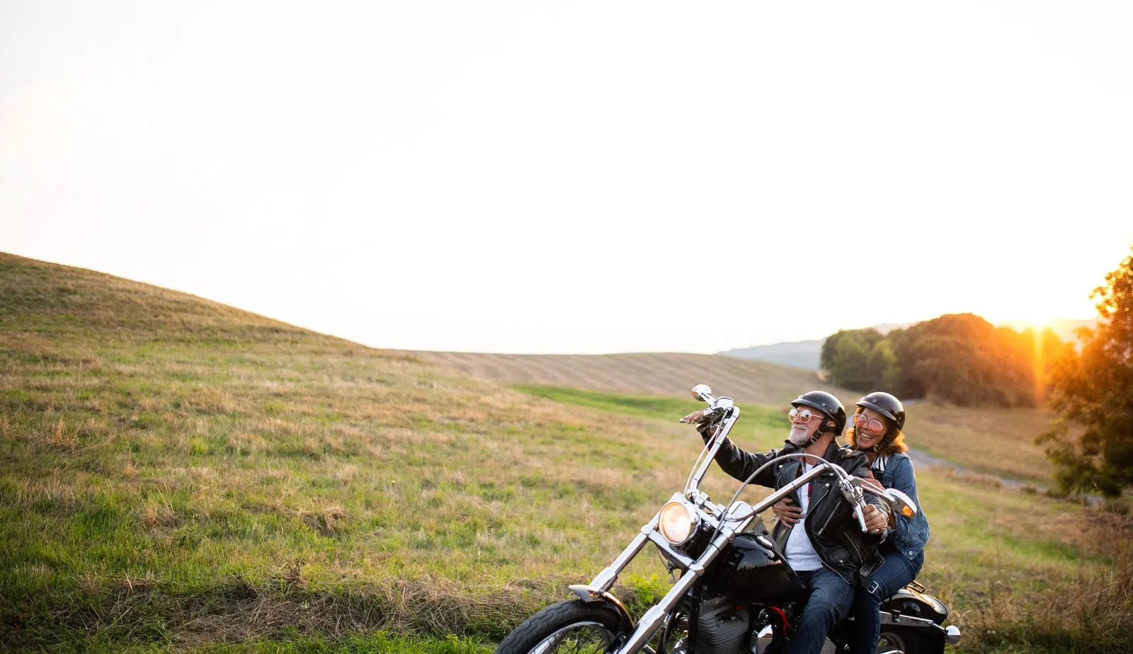 Um alegre casal sênior viajantes com moto no campo. - Fotos do Canva1