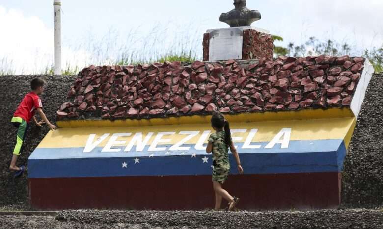 Crianças brincam em marco da fronteira entre Brasil e Venezuela.