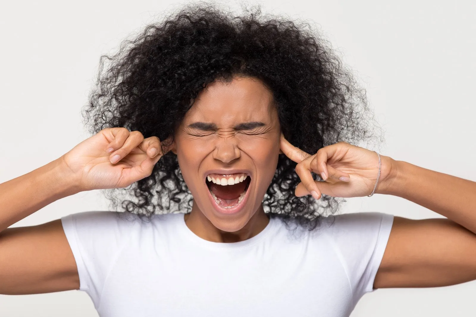 Mulher negra teimosa e irritada enfiando os dedos nos ouvidos - Fotos do Canva1