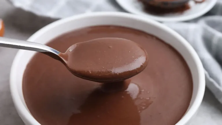 Cena aconchegante com uma xícara de chocolate quente cremoso fumegante em uma mesa com um suéter de lã e cobertores macios ao redor, perfeita para aquecer nos dias frios