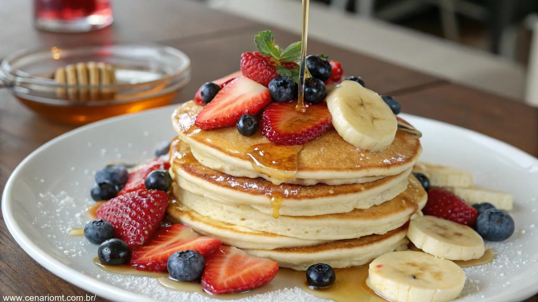 Uma pilha de panquecas americanas fofinhas com frutas frescas e mel.