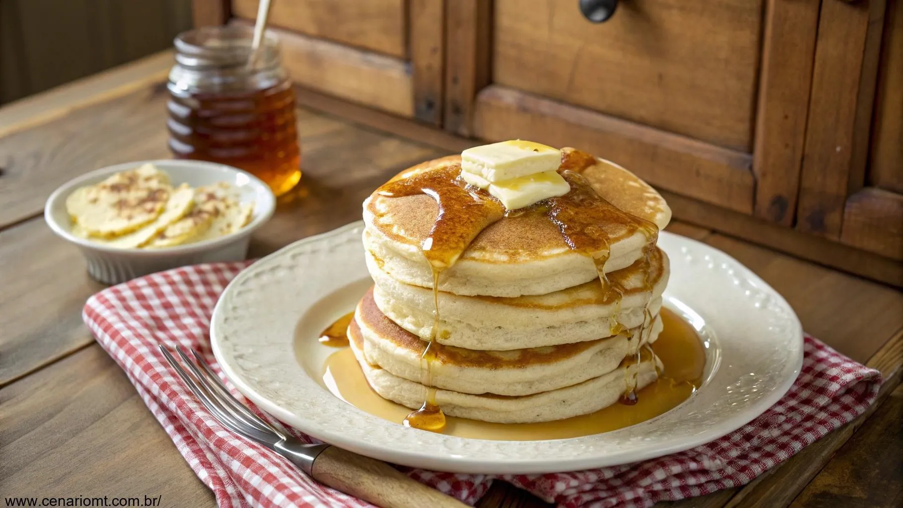 Vista superior de uma pilha de panquecas americanas fofinhas em um prato branco, cobertas com manteiga derretida e regadas com xarope dourado, em uma mesa de madeira com fundo de cozinha rústica.