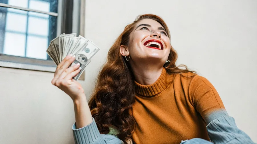 Mulher sorrindo com dinheiro na mão