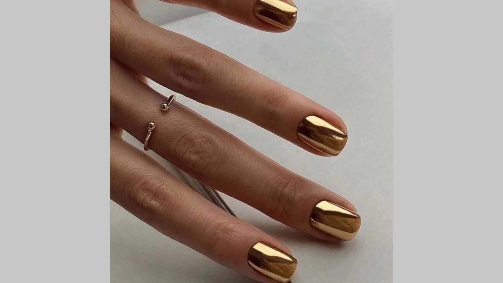 Manicure dourada elegante para unhas curtas com detalhes em folha de ouro.