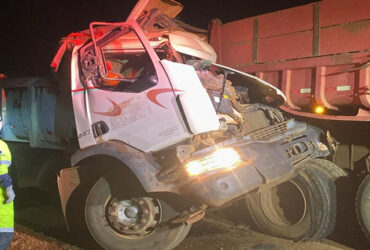 Colisão traseira entre caminhões resultou na morte de um funcionário que atuava na duplicação da rodovia; autoridades investigam as causas.