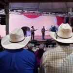 Palco do Encontro Nacional de Violeiros de Poxoréu durante apresentação da viola caipira, com público reunido no Parque de Exposições.