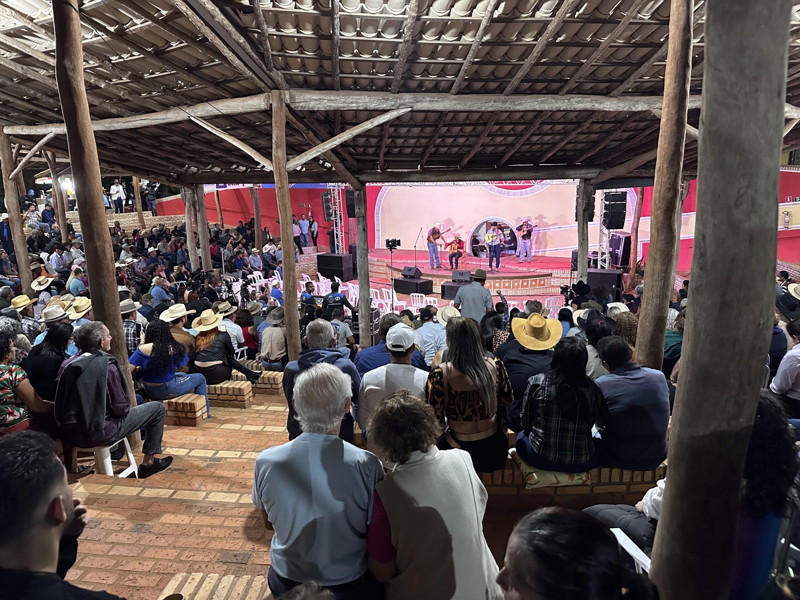 Palco do Encontro Nacional de Violeiros de Poxoréu durante apresentação da viola caipira, com público reunido no Parque de Exposições.