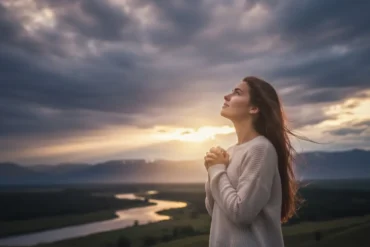 Imagem que ilustra uma Mulher com as mãos postas em oração olhando para o céu estrelado em um momento de fé e silêncio.