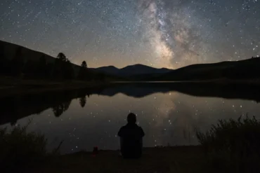 Noite tranquila com céu estrelado e lago refletindo luz suave