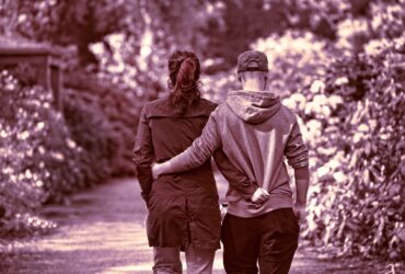 Casal andando abraçado em meio à natureza