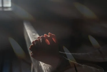 Oração da noite católica em ambiente silencioso com Bíblia, vela acesa e clima de paz