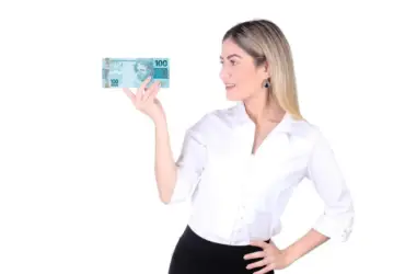 Mulher segurando nota de 100 reais na mão