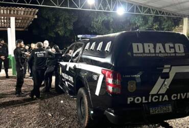 Policiais civis ao lado de viatura da DRACO