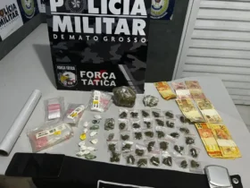 Foto das drogas apreendidas pela força tática, todas estão enfileiradas em uma mesa juntamente a dinheiro sujo e outros itens apreendidos