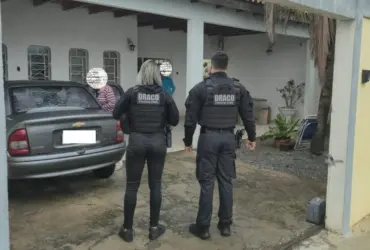 Foto de oficiais da Draco conversando com moradores de uma residência