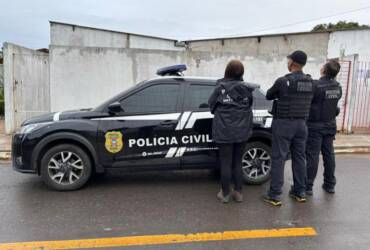 Foto de policiais civis em frente à viatura