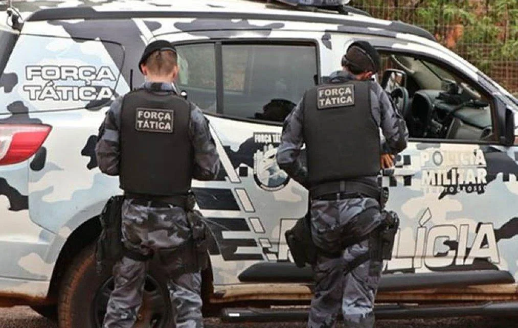 Policiais militares da força tática ao lado de viatura