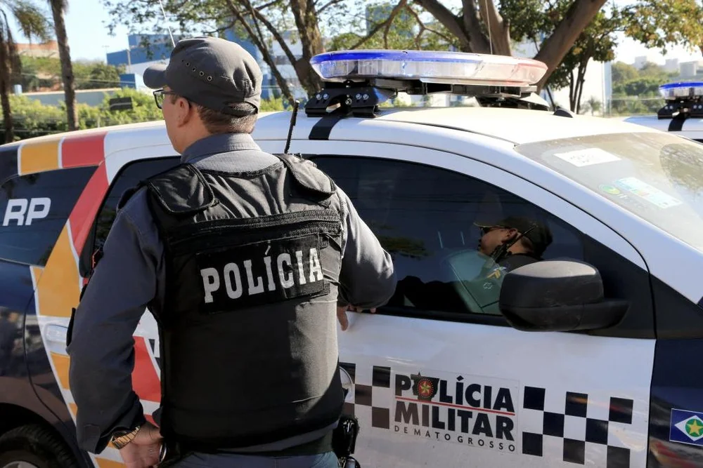 Policial militar ao lado de viatura